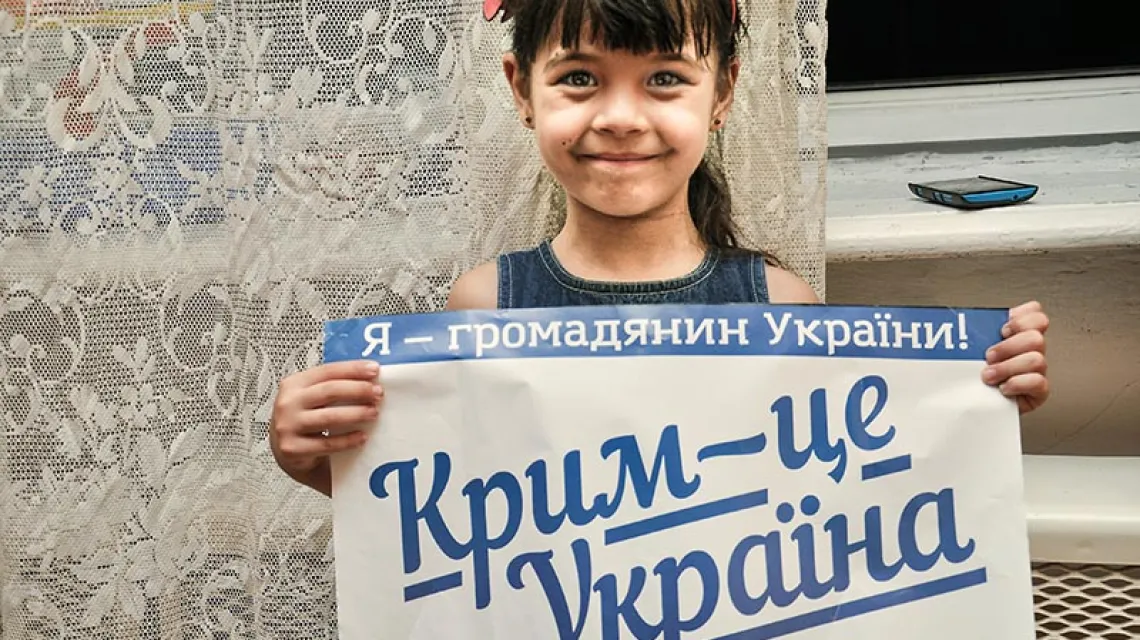 „Jestem obywatelem Ukrainy! Krym to Ukraina” – głosi plakat trzymany przez Kamilę. Dziewczynka wraz z ojcem uciekła z Krymu po rosyjskiej agresji. Drohobycz, lipiec 2015 r. / Fot. Monika Andruszewska