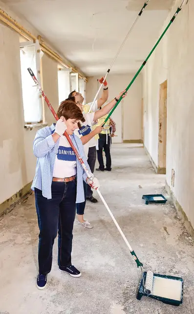Beata Szydło w trakcie kampanii wyborczej pomaga przy malowaniu zniszczonej przez wichury szkoły podstawowej w Pcimiu, sierpień 2015 r. / Fot. Jacek Bednarczyk / PAP