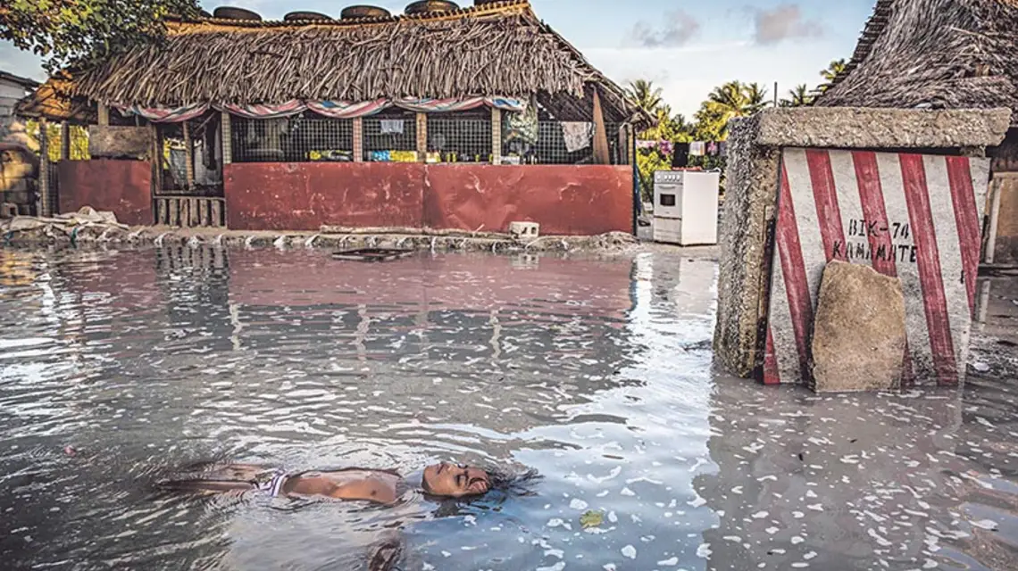 Dziecko pływa w zalewanej przez ocean osadzie na wyspie Tarawa, głównym atolu państwa Kiribati. / Fot. Jonas Gratzer / GETTY IMAGES