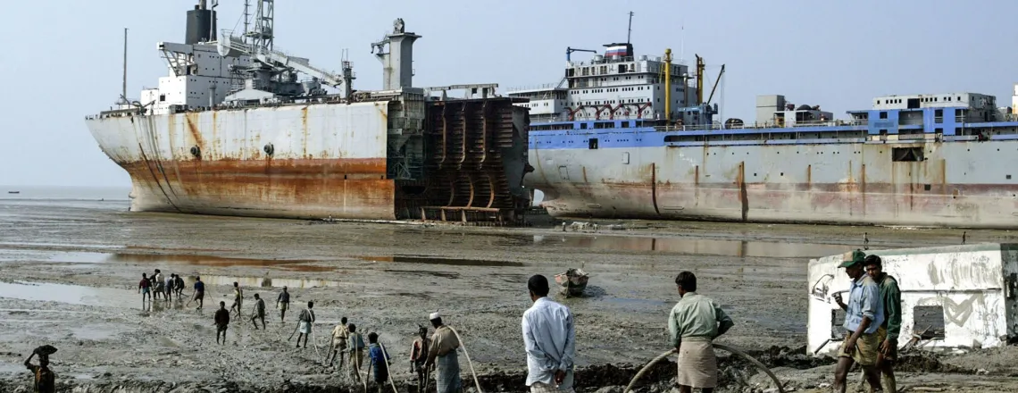 Robotnicy rozwijają przewód do palnika gazowego, którym będą wycinać metalowe części zezłomowanego statku. Ćittagong, Bangladesz, grudzień 2004 r. // Fot. AMAN SHARMA / AP / East News