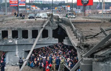 Uciekinierzy  z Kijowa pod mostem zniszczonym  w wyniku rosyjskiego nalotu czekają na ewakuację.  Irpień, przedmieścia ukraińskiej stolicy,  5 marca 2022 r. / EMILIO MORENATTI / AP / EAST NEWS