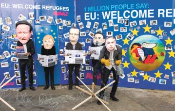 Aktorzy przebrani za unijnych polityków trzymają okładki gazet, w których ukazało się zdjęcie Aylana Kurdiego, 3-latka, który utonął podczas przeprawy do Europy. Bruksela, 14 września 2015 r. / Fot. Virginia Mayo / AP / EAST NEWS