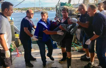 Pietro Bartolo (trzeci od lewej) podczas akcji pomocy migrantom na nabrzeżu Lampedusy. / Fot. Nino Randazzo