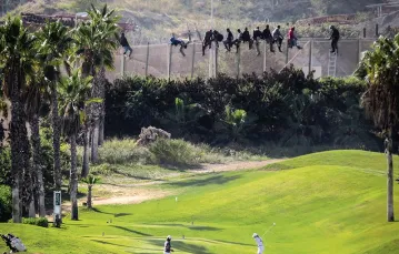 Afrykańscy migranci na ogrodzeniu pola golfowego w hiszpańskiej enklawie Melilla w Maroku, 22 października 2014 r. / Fot. STRINGER / REUTERS / FORUM