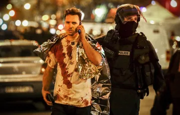 Policjant eskortujący ocalałego z zamachu w paryskim klubie Bataclan, 13 listopada 2015 r. / Fot. Philippe Wojazer / REUTERS / FORUM