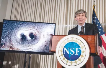 David Reitze z laboratorium LIGO ogłasza, że jego zespół zaobserwował fale grawitacyjne. Na monitorze wizualizacja zderzenia dwóch czarnych dziur. Waszyngton, 11 lutego 2016 r. / Fot. Saul Loeb / AFP / EAST NEWS