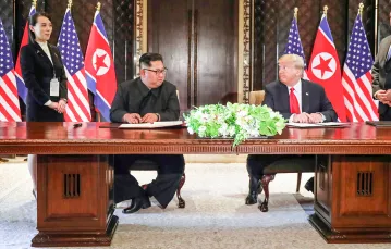 Przywódca Korei Płn., Kim Dzong Un podpisuje poozumienie z prezydentem USA Donaldem Trumpem. Obok stoją: Kim Yo Jong, siostra koreańskiego dyktatora, i  Mike Pompeo, sekretarz stanu USA. Singapur, czerwiec 2018 r. // Fot. JONATHAN ERNST / Reuters / Forum
