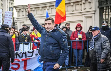 37-letni George Simion (z podniesioną ręką), lider Związku Jedności Rumunów, pozdrawia sympatyków podczas protestu przed parlamentem w Bukareszcie. 21 grudnia 2021 r. / Fot. Daniel Mihailescu / AFP / East News