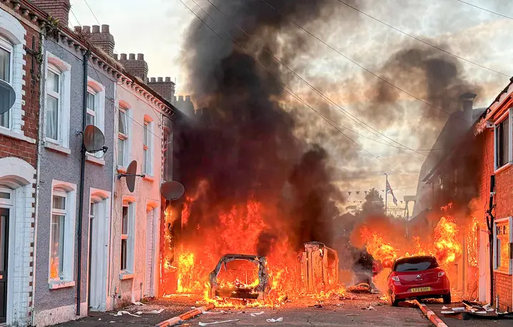 Samochody płonące na ulicach Belfastu. Podczas antyemigranckich zamieszek doszło do niszczenia mienia i przemocy wobec osób o ciemnej skórze. Belfast, 9 czerwca 2026 r. // Fot. PA / PAP