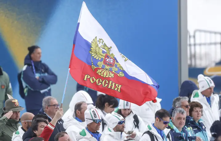 Kibice z rosyjskimi flagami podczas ceremonii medalowej biegu paraolimpijskiego mężczyzn na 20 km. Zwycięzca, rosyjski zawodnik Iwan Gołubkow, rywalizował jako sportowiec neutralny, zgodnie z zasadami obowiązującymi rosyjskich uczestników igrzysk. Włochy Val di Fiemme (Tesero), Włochy, 15 marca 2026 r. // Fot. Darrian Traynor / Getty Images