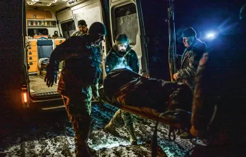 Medycy transportują rannego żołnierza. Po środku z czołówką to Ołeksandr. Obwód doniecki, luty 2023 r. / PAWEŁ PIENIĄŻEK