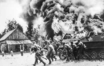 Niemieccy żołnierze w natarciu, w tle płonąca polska wioska. Wrzesień 1939 r. / BEW