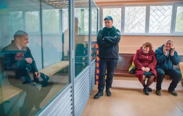Ołeksandr Tkaczenko pokazuje synowi Witalijowi, że jest ładnie ogolony. To jeden z nielicznych uśmiechów, który wymienili na sali sądowej. 13 kwietnia 2023 r. / PAWEŁ PIENIĄŻEK