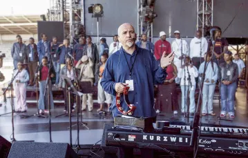 Peter Gabriel  na próbie z chórem  przed koncertem „46664 – Poświęć minutę swego życia dla AIDS”. W koncercie tym wzięli też udział Bono, Queen, Eurythmics i wielu afrykańskich muzyków. Kapsztad, RPA, listopad 2013 r. / FRANK MICELOTTA / GETTY IMAGES