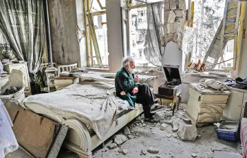 Abu Omar, 70-letni mieszkaniec syryjskiego Aleppo, słucha nagrań na gramofonie w swoim zniszczonym podczas walk domu, 2017 r. / JOSEPH EID / AFP / EAST NEWS