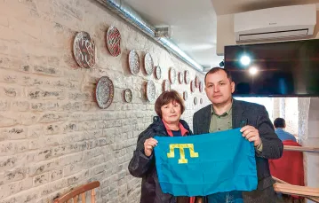 Erfan Kudusow często fotografuje się ze swoimi gośćmi i z flagą Tatarów Krymskich, restauracja Czeburek, Kijów, wrzesień 2019 r. / ARCHIWUM ERFANA KUDUSOWA