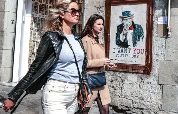 Turystki na ulicach, w tle graffiti „Chcę, abyś został w domu”, Barcelona, 13 marca 2020 r. / MIQUEL BENITEZ / GETTY IMAGES