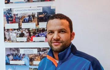Ali Boujerfaoui na tle zdjęć przedstawiających działania fundacji Mil Caminos. Salamanka, 28 października 2022 r. / AGNIESZKA ZIELIŃSKA
