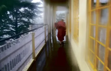 Stary mnich biegnie w podmuchach ulewy na tarasie świątyni Dalajlamy Tsuglagkhang, Dharamsala, maj 2008 /fot. Bartek Dobroch / 