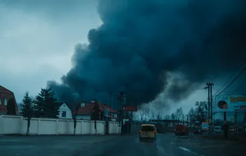 Ewakuowani cywile mijają słup dymu unoszący się znad składów na obrzeżach Kijowa / fot. Paweł Pieniążek / 