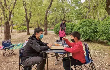 Ojciec gra z synem w wuziqi, tradycyjną chińską grę. Park Chaoyang w Pekinie, kwiecień 2020 r. / LÜ JIAN