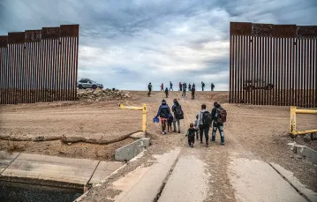 Rodziny pochodzące z Haiti przechodzą z Meksyku na terytorium Stanów Zjednoczonych przez dziurę w murze granicznym w ­miejscowości Yuma w stanie Arizona, 10 grudnia 2021 r. / JOHN MOORE / GETTY IMAGES