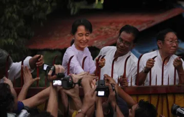 Aung San Suu Kyi przed bramą spornej posiadłości w czasach osadzenia w areszcie domowym, 2010 r. / Fot. AP / East News / 