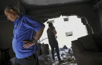 Izraelska rodzina ogląda zrujnowane mieszkanie po uderzeniu palestyńskiej rakiety, Petah Tikva (środkowy Izrael), 13 maja 2021 r. / Fot. Oded Balilty / AP Photo / East News / 