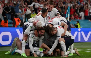 Harry Kane (z kapitańską opaską) tonie w objęciach kolegów po zwycięskim golu dla Anglii w półfinałowym meczu z Danią, 7 lipca 2021 r. / FOT. LAURENCE GRIFFITHS / AFP / EAST NEWS / 