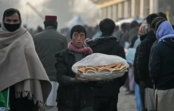 Mężczyzna sprzedaje chleb w kolejce do biura paszportowego w Kabulu, 19 grudnia 2021 / fot. MOHD RASFAN/AFP/East News / 