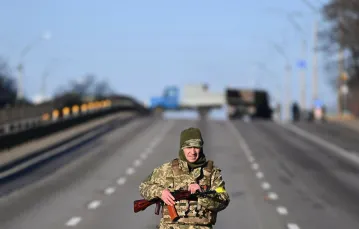 Ukraiński żołnierz patroluje drogę po zachodniej stronie Kijowa rankiem 26 lutego 2022 r. Fot. DANIEL LEAL/AFP/East News / 