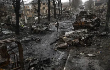 Kobieta idzie wśród zniszczonych rosyjskich czołgów. Bucza, 3 kwietnia / fot. AP/Associated Press/East News / 