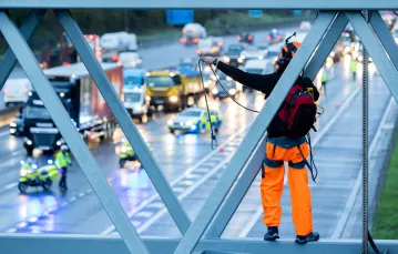Aktywista z grupy ekologicznej Just Stop Oil, wspina się nad autostradą M25 we wschodnim Londynie, podczas porannych godzin szczytu, 9 listopada 2022 r. / fot. Marcin Nowak/REPORTER / 