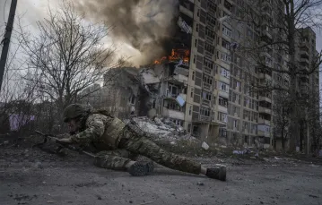 Ukraiński policjant przed budynkiem trafionym przez rosyjską rakietę. Awdijiwka, Ukraina, 17 marca 2023 r. / fot. Evgeniy Maloletka/Associated Press/East News / 