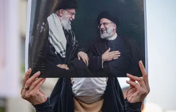 Zwolenniczka Ebrahima Raisiego z plakatem, na którym widnieje on (z prawej strony) w towarzystwie swego mentora Alego Chamenei. Teheran, 11 czerwca 2021 r. / MORTEZA NIKOUBAZL / NURPHOTO / AFP / EAST NEWS