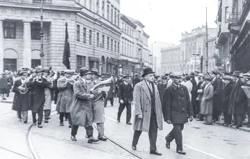 Pochód PPS, Warszawa, 1 maja 1931 r. Orkiestra wchodzi z ulicy Bielańskiej na plac Teatralny. W głębi ulicy po prawej widoczny gmach Banku Polskiego. / NAC