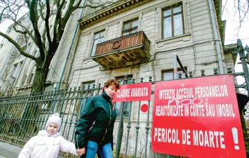 Przechodnie przed kamienicą oznaczoną czerwoną kropką i napisem „Uszkodzony budynek”, „Niebezpieczeństwo śmierci”. Na dwa dni przed 40. rocznicą trzęsienia z 1977 r. i na dzień przed fałszywym alarmem, który poderwał kilkaset tysięcy mieszkańców rumuńskie / DANIEL MIHAILESCU / AFP