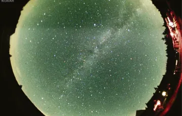 Dopiero w prawdziwych ciemnościach można podziwiać gwiazdy w całej krasie. Zdjęcie z szerokokątnej kamery obejmującej całe niebo. Po przekątnej biegnie Droga Mleczna. W prawym dolnym rogu budynek schroniska "Orle". Sierpień 2012 r. / Fot. Sylwester Kołomański
