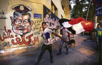 Mursi i Mubarak, dwaj byli prezydenci Egiptu, na graffiti naprzeciw Ministerstwa Kultury. Kair, 30 czerwca 2013 r.  / Fot. Hiro Komae / AP / EAST NEWS