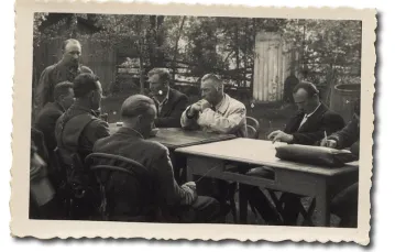 Negocjacje w Lublińcu. Przy stole pierwszy od lewej Łopatynśkyj, obok Martyniuk (obaj tyłem), naprzeciw w białym płaszczu Gołębiewski. Mężczyzna obok, który uderza palcami w blat stołu, to kapitan Stanisław Książek „Rota”. 21 maja 1945 r. / Zdjęcie z archiwum Stanisława Książka / ZBIORY MARIUSZA ZAJĄCZKOWSKIEGO