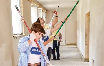 Beata Szydło w trakcie kampanii wyborczej pomaga przy malowaniu zniszczonej przez wichury szkoły podstawowej w Pcimiu, sierpień 2015 r. / Fot. Jacek Bednarczyk / PAP