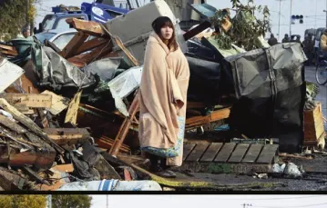 U góry: Yuko Sugimoto szuka syna w dotkniętym przez tsunami mieście Ishinomaki – 13 marca 2011 r. | U dołu: W tym samym miejscu rok później, wraz z odnalezionym pięcioletnim synem, Raito – 27 stycznia 2012 r. / fot. Toru Yamanaka / AFP / East News