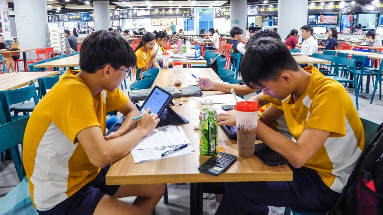 Uczniowie Queenstown Secondary School przygotowują się do egzaminu z nauk przyrodniczych. Dzieci i młodzież ucząca się w jadłodajniach lub kawiarniach to częsty widok w Singapurze. Uczniowie od najmłodszych lat przyzwyczajani są do nauki wieczorami i w weekendy. Singapur, wrzesień 2023 r. / Fot. Marta Zdzieborska