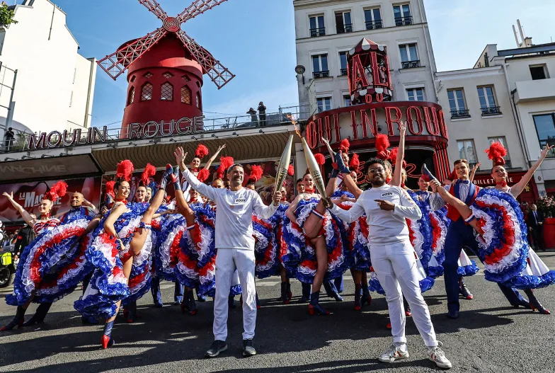 Sztafeta z olimpijskim ogniem prebiega przez najbardziej znane miejsca w Paryżu. Na zdjęciu: przed kabaretem Moulin Rouge, 15 lipca 2024 r. // Fot. Stephanie Lecocq / Reuters / Forum