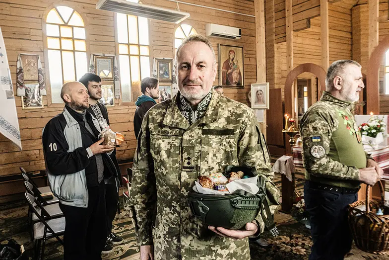 Żołnierz Leonid ze święconką w hełmie podczas niedzielnego nabożeństwa w cerkwi grekokatolickiej pw. św. Eljasza, 12 kwietnia // Fot. Antonina Palarczyk
