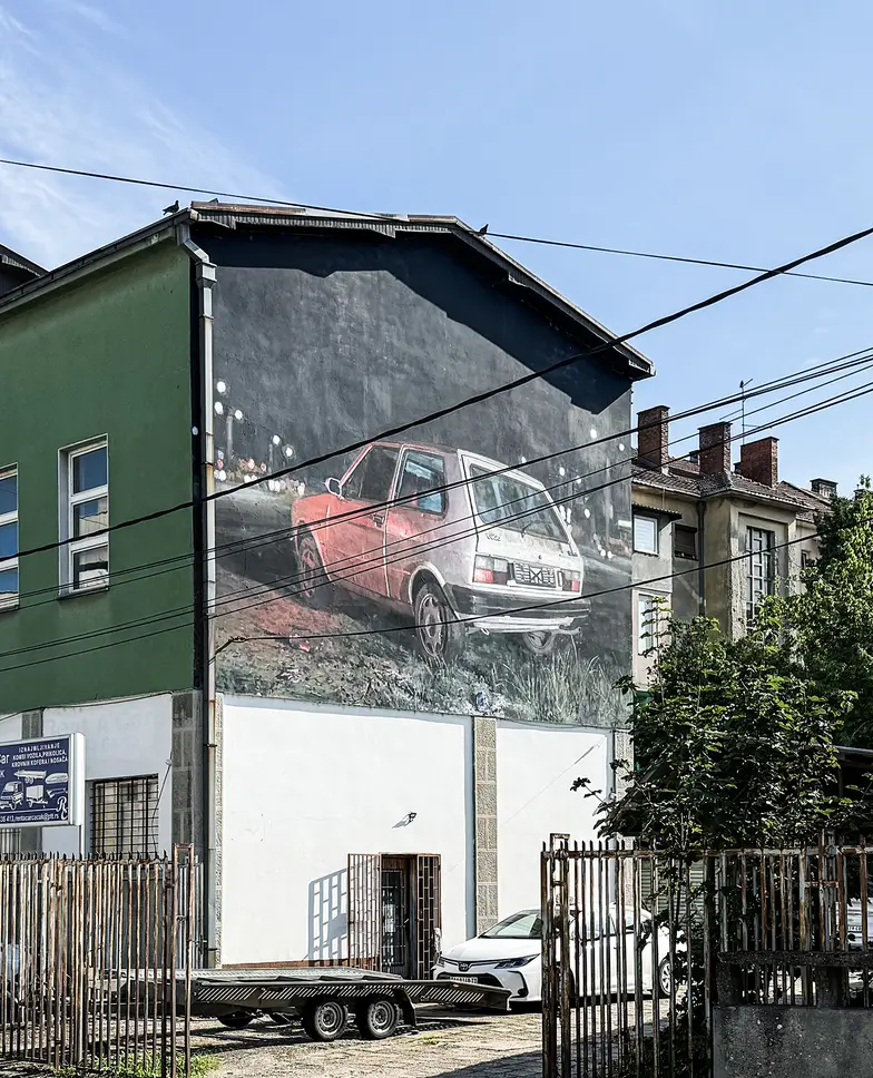 Samochód jugo 45 na muralu w miasteczku Čačak. Było to popularne auto osobowe w Jugosławii, a dziś jest symbolem dla tych, którzy tęsknią za dawnymi czasami. Lipiec, 2026 r. // Fot. Juliusz Pielichowski Samochód jugo 45 na muralu w miasteczku Čačak. Było to popularne auto osobowe w Jugosławii, a dziś jest symbolem dla tych, którzy tęsknią za dawnymi czasami. Lipiec, 2026 r. // Fot. Juliusz Pielichowski