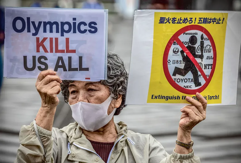 „Olimpiada zabija nas wszystkich”: protest podczas ceremonii przyjęcia sztafety olimpijskiej na stadionie w Tokio, 9 lipca 2021 r. W związku z rozwojem epidemii władze nie pozwoliły sztafecie biec ulicami, aby uniknąć zgromadzeń.