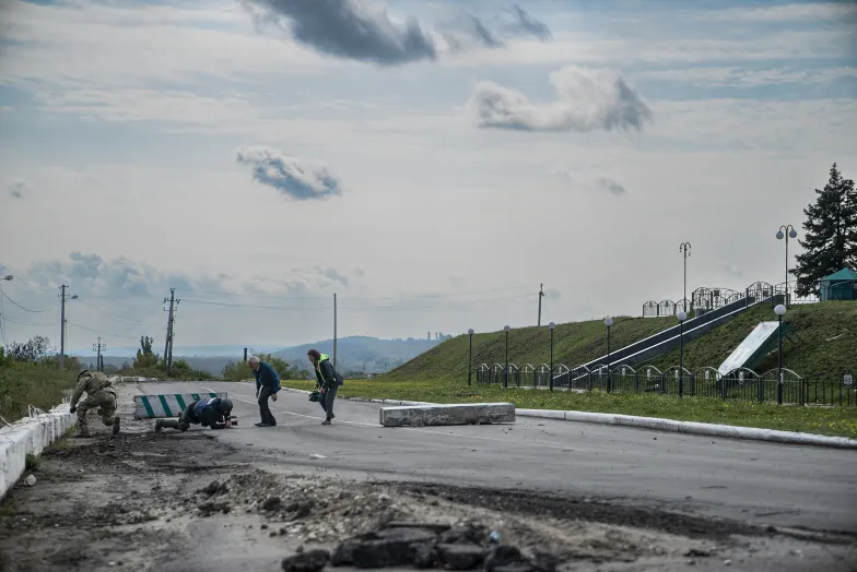 Ludzie padają na ziemie w trakcie ostrzału Kupiańska.wrzesień 2022 r./ FOT. PAWEŁ PIENIĄŻEK