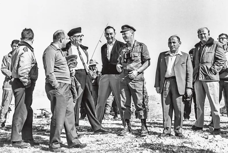 Premier Lewi Eszkol (czwarty odlewej, wczarnej czapce ipod krawatem), szef Mossadu Meir Amit (pośrodku, uśmiechnięty), szef sztabu Icchak Rabin (wmundurze) ibyły dyrektor Mossadu Isser Harel (trzeci od prawej), 1965 r.