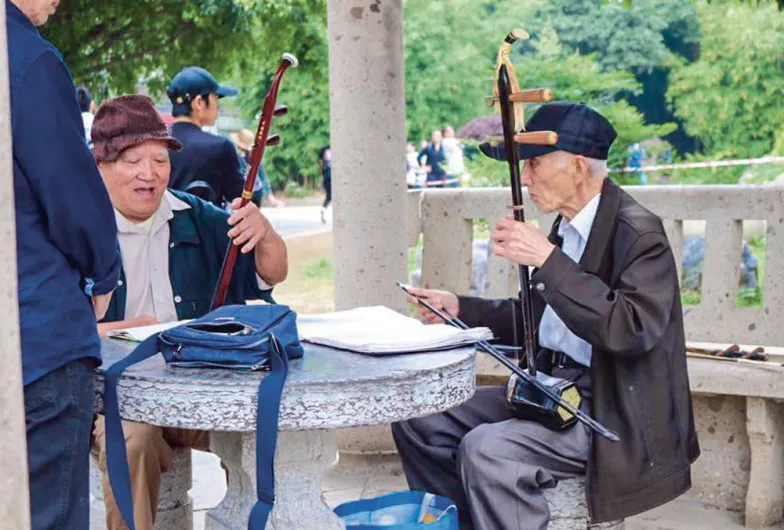 Mężczyźni grają na erhu, tradycyjnych chińskich skrzypcach. Park Xiangbishan w mieście Guilin w południowych Chinach, lipiec 2019 r.